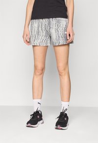Calças de desporto cinzentas estampadas com um corte descontraído; combinadas com sapatilhas pretas e meias brancas. Design simples, adequado para vestuário ativo.