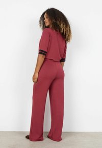 Set de haine pentru relaxare bordo, cu un top cu mâneci scurte și accente cu dungi negre, și pantaloni largi cu talie elastică. Textură netedă.