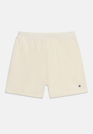 Pantalones cortos casuales de color crema con cintura elástica y un pequeño logo rojo, blanco y azul en la parte inferior de la pierna derecha.