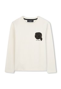 Chemise à manches longues crème avec texture côtelée, présentant un design noir brodé de lunettes de soleil et d'une silhouette de tête sur la poitrine.