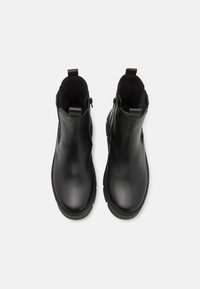 Black leather ankle boots with side cutouts and zippers, featuring a smooth surface and rubber soles for traction.