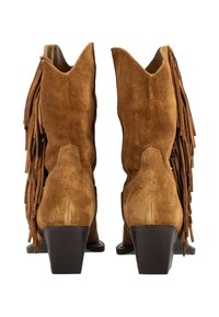 Brązowe zamszowe kowbojskie buty na obcasie z frędzlami po bokach, widziane od tyłu na białym tle.
