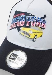 Grau und schwarze verstellbare Kappe mit "Grüße aus NEW YORK" in Rot, Weiß und Blau. Ikonische Grafik eines gelben Taxis und New Era-Label.