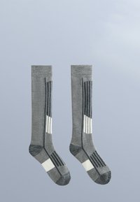 Para szarych skarpetek do kolan z ciemnoszarymi i białymi geometrycznymi paskami na jasnoniebieskim tle.