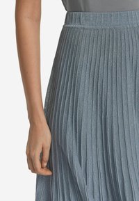 Fodrad kjol i ljusblått, tillverkad av ett skimrande tyg. Har en texturerad yta och ett elastiskt midjeband för komfort.