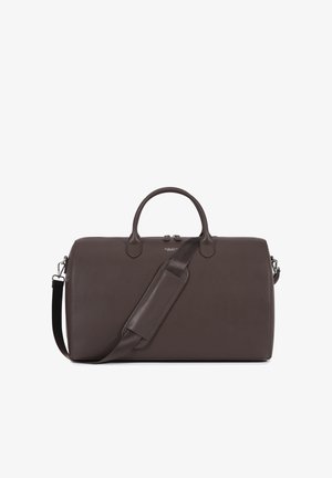 Sötétbarna bőr utazótáska lekerekített fogantyúkkal, levehető vállpánttal, amely párnázott részt tartalmaz, és apró ezüst logóval az elülső részén.