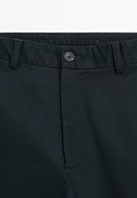 Chinos bleu marine foncé en mélange de coton lisse, avec une taille plate, une ceinture standard et une fermeture à un bouton.