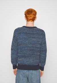 Hřejivý pletený svetr v tmavě modré a světlejší modré barvě. Má žebrovaný výstřih a manžety, s texturovaným tkaným vzorem.