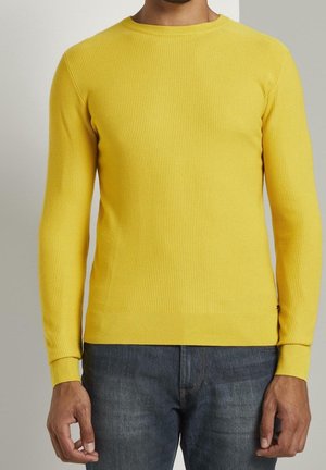 Geel geribbeld sweater met een ronde halslijn en lange mouwen, gemaakt van gladde katoen. Gecombineerd met donkerblauwe denimjeans.