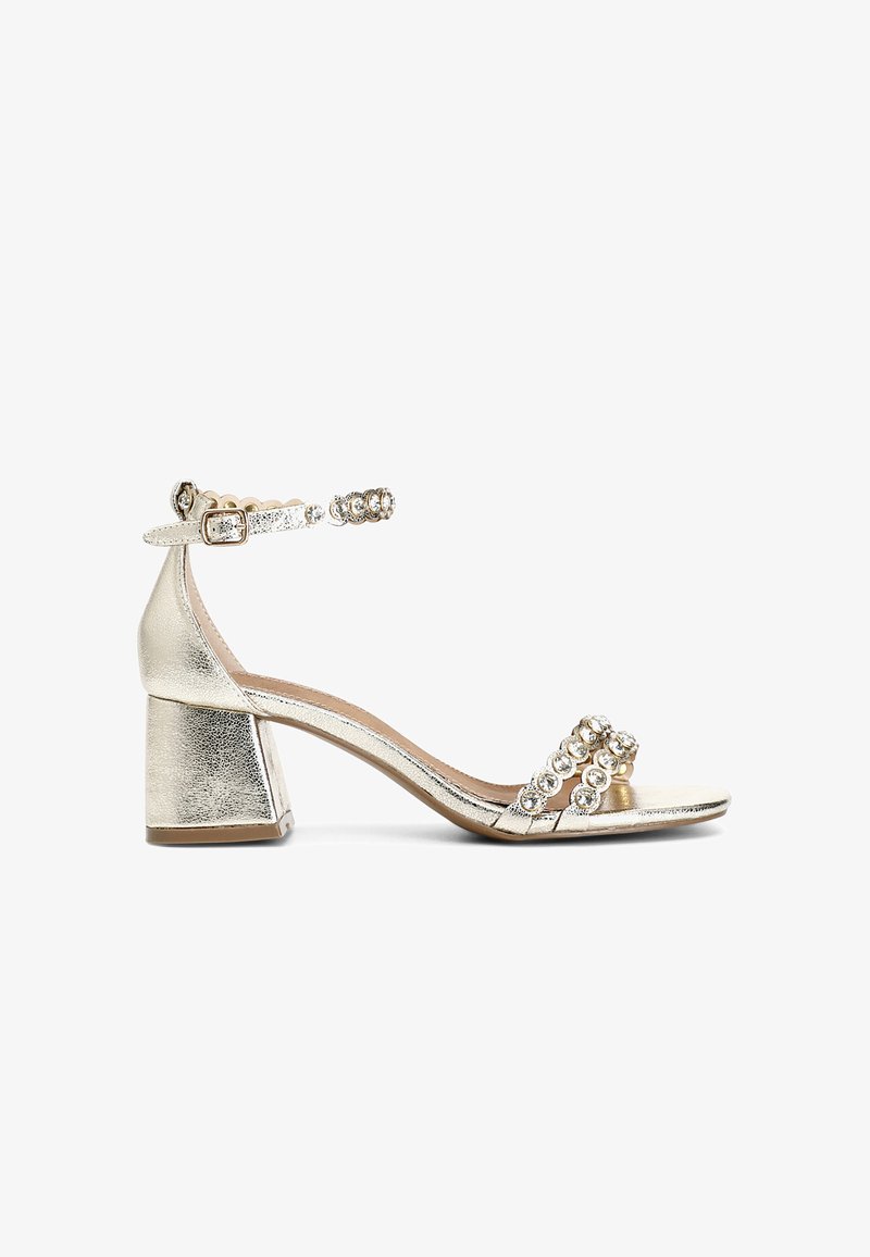 Kulta metalliset korkokengät, joissa on lohkokorko, koristeellinen nilkkahihna pyöreillä jalokivikoristeilla ja kaksi etuhihnaa.