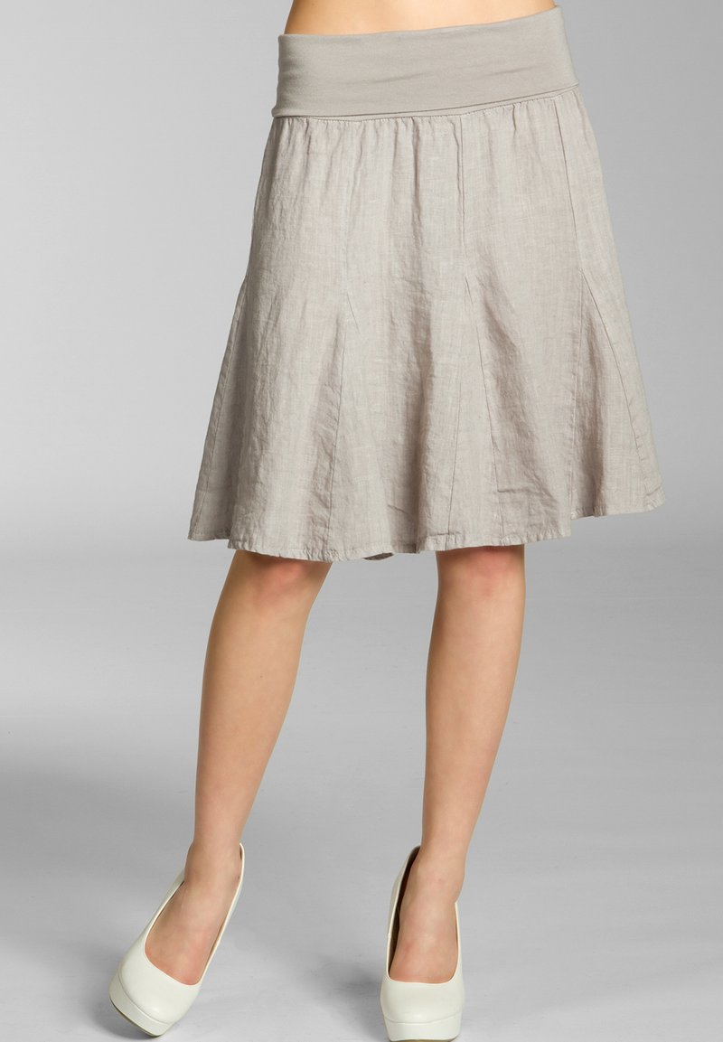 Beige Leinen-A-linien-Rock mit einem breiten elastischen Bund, knielang und mit dezenten Falten für zusätzliche Textur. Getragen mit weißen Absätzen.