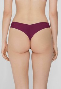 Bordowe majtki bikini o niskim stanie i gładkiej fakturze, z prostym wzornictwem i minimalnym zakryciem z tyłu.