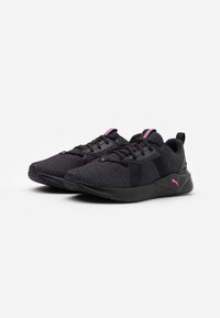 Zapatillas deportivas negras con parte superior de malla texturizada, acentos rosas, cordones planos y suela negra acolchada diseñada para brindar comodidad y soporte.