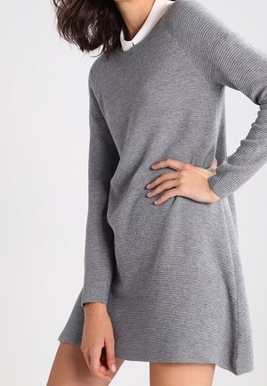 Abito maglione grigio a coste con maniche lunghe e colletto bianco. Presenta una vestibilità rilassata e un orlo leggermente svasato per favorire il movimento.