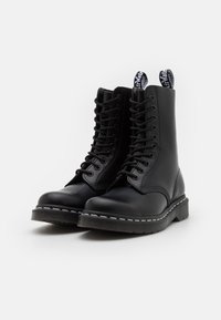 Stivali neri in pelle con allacciatura, finitura liscia, punte arrotondate, suole spesse, cuciture bianche e linguette con marchio bianco e nero.