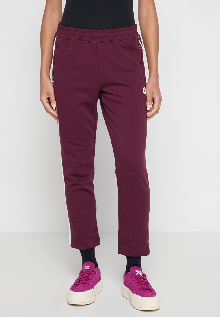 Pantalones de chándal color burdeos hechos de una tela suave, con cintura ajustable, bolsillos laterales y un corte ajustado que se estrecha hacia los tobillos.