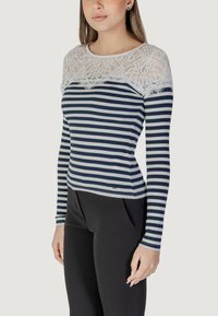 Maglietta a maniche lunghe con yoke in pizzo bianco e corpo a righe blu navy in cotone misto, con vestibilità slim e scollatura rotonda. Orlo decorato.