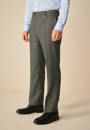Pantalones grises a cuadros con un corte ajustado, que presentan un frente plano y cinturilla. Combinados con una camisa azul clara y zapatos de vestir negros.