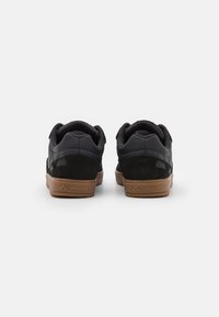 Czarne sneakersy z połączeniem strukturalnej skóry i zamszu. Posiadają gumową podeszwę i widoczne logo na pięcie.