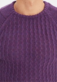 Violetti neulottu villapaita, jossa on teksturoitu joustinneulos, pyöreä pääntie ja raglanhihat. Materiaali vaikuttaa pehmeältä ja lämpimältä.