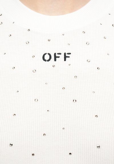 Λευκό ριμπ ύφασμα με μικρές λαμπερές τρουκς και τη λέξη «OFF» κεντημένη με μαύρα γράμματα στο κέντρο.
