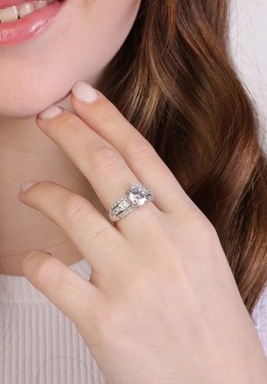 Bague en argent avec une grande pierre centrale transparente et de petites pierres d'accent le long d'un réglage à double bande. Fini lisse et poli.