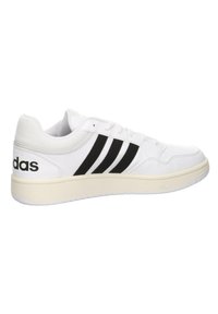 Białe sneakersy z czarnym wzorem w trzy paski, skórzana cholewka, zaokrąglony czubek, wyściełany kołnierz i teksturowana gumowa podeszwa. Logo "Adidas" z boku.