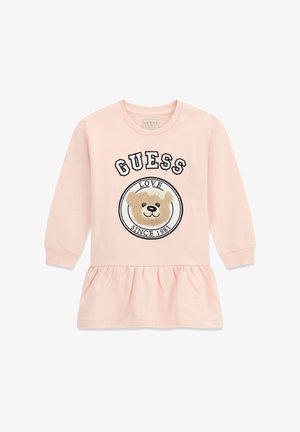 Jasnoróżowa sukienka z długim rękawem i marszczonym dołem, z misiem i napisem "GUESS LOVE SINCE 1981" na przodzie.