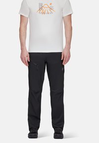 Svarta utomhusbyxor med smal passform, som har sidofickor med dragkedja, lätt material och en subtil logotyp på vänster lår.