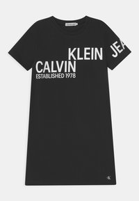 Černé bavlněné tričko s výrazným bíl�ým textem: "CALVIN KLEIN JEANS ZALOŽENO 1978." Kulatý výstřih a krátké rukávy, s logem.