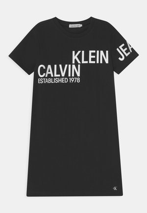 Czarna bawełniana koszulka z wyraźnym białym napisem: "CALVIN KLEIN JEANS ZAŁOŻONA W 1978 R." Okrągły dekolt i krótkie rękawy, z akcentem logo.