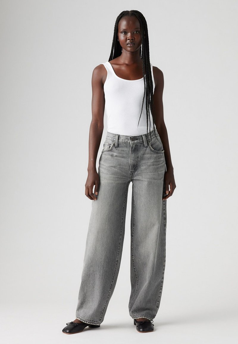 Gray wide-leg jeans with a high waist and five pockets, paired with a fitted white tank top. Material appears denim with a soft texture.