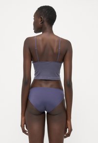 Paarse cropped tanktop met dunne bandjes, gecombineerd met bijpassende low-rise bikini slipjes, die een gladde, rekbare stof en een minimalistisch ontwerp laten zien.