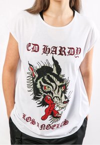 Camiseta de algodón blanca con mangas cortas que presenta un gráfico de tigre negro y rojo adornado con piedras de strass, texto "ED HARDY" arriba y "LOS ÁNGELES" abajo.