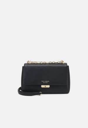 Sac à bandoulière en cuir noir Kate Spade New York avec poignée chaîne dorée et fermeture à clip sur fond uni.