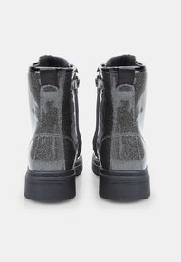Botas de tobillo negras con purpurina y acabado brillante, que cuentan con cremalleras laterales, suelas texturizadas y lengüetas en la parte superior para facilitar su puesta.