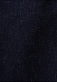 Tmavě modrá džínovina s viditelnou diagonální strukturou tkaní a malými bílými tečkami po celé ploše.