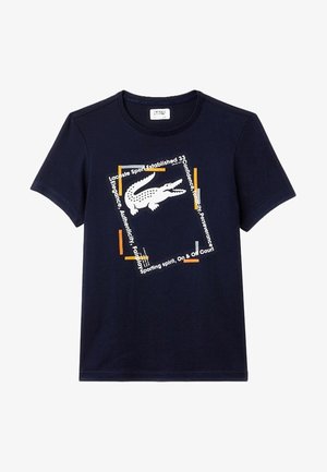 T-shirt bleu marine à manches courtes avec un logo crocodile blanc centré à l'intérieur d'un cadre carré incliné avec un texte orange et blanc.