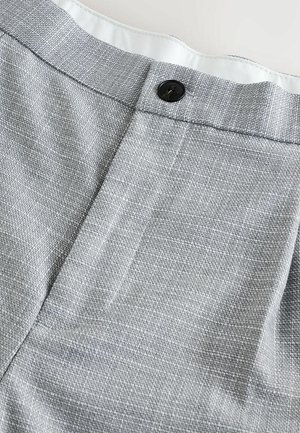 Grått tyg med en texturerad väv, som har en svart knappstängning och en slät inredning. Designen är skräddarsydd med en ren finish.