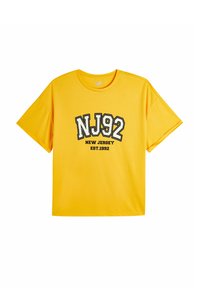 Keltainen lyhythihainen t-paita pehmeästä kankaasta, etupuolella mustavalkoinen graafinen printti: "NJ92 NEW JERSEY EST.1992".