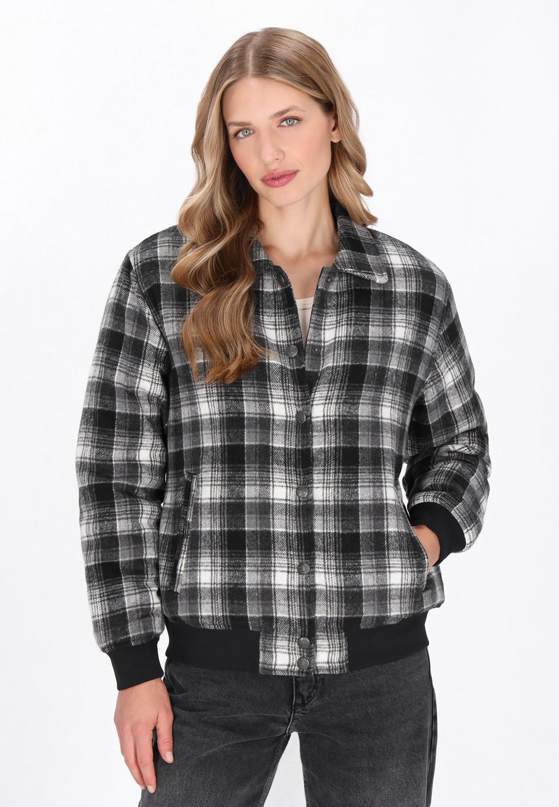 Fekete-fehér kockás dzseki, galléros nyakkal, gombos záródással, oldalsó zsebekkel és bordás mandzsettával és szegéllyel. Puha anyagból készült.