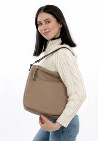 Sac à épaule en cuir tan avec une texture lisse, doté d'un dessus zippé, d'une longue sangle et d'un tirette décorative. Design simple et fonctionnel.
