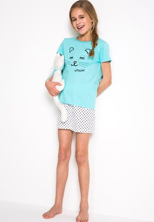T-shirt di cotone azzurro chiaro con un design di volto di gatto e testo "#meow!", abbinato a pantaloni corti bianchi con pois neri.