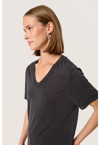Tricou negru cu decolteu în V, realizat dintr-un material moale, cu mâneci scurte și o croială lejeră. Prezintă o textură subtilă și un design simplu.