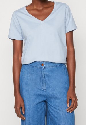 T-shirt blu chiaro a maniche corte con scollo a V abbinato a pantaloni in denim blu a vita alta con chiusura a bottone. Tessuto dalla consistenza morbida.