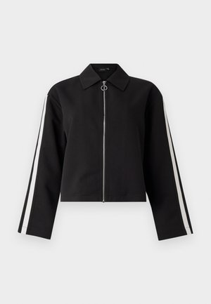 Black cropped jacket with long sleeves, silver zipper, and side stripes. Features a pointed collar and ring pull detail. Smooth fabric texture.