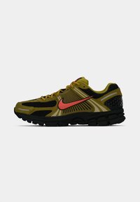 Olivovo zelené a čierne bežecké topánky Nike s oranžovým Swooshom a reflexnými akcentmi, bočný pohľad na bielom pozadí.