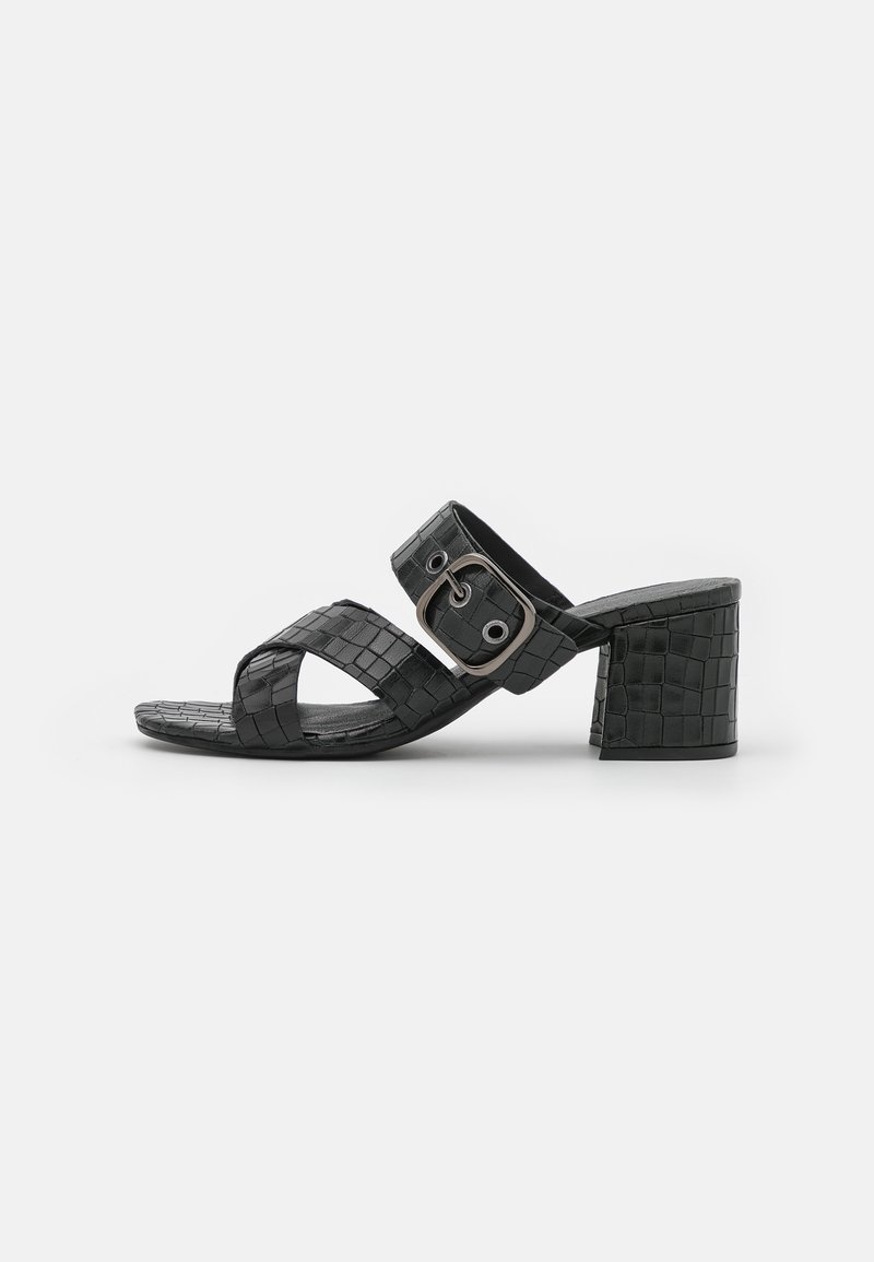 Sandales à talons blocs en cuir synthétique noir avec des brides croisées et un détail de boucle carrée, présentant un motif texturé effet peau de crocodile.
