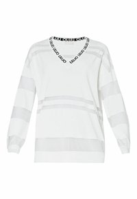 Maglione bianco con scollo a V, con strisce nere con logo lungo il colletto e motivi a strisce orizzontali grigie sulle maniche. Tessuto morbido.
