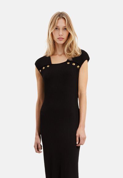 Zwart geribbeld jurkje met een vierkante halslijn, korte mouwen en gouden knoopaccenten op de schouder. Gladde textuur en aansluitende silhouette.